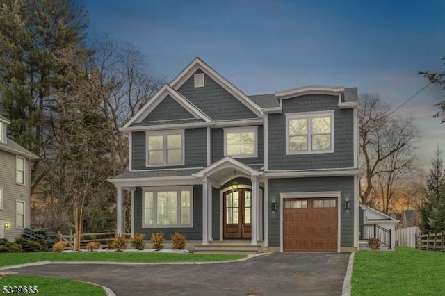 view of front of house featuring french doors, an attached garage, fence, driveway, and a front lawn