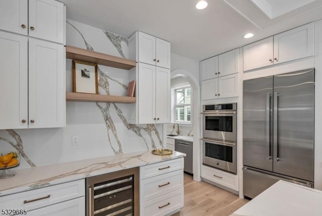 kitchen with light stone counters, wine cooler, open shelves, appliances with stainless steel finishes, and white cabinets