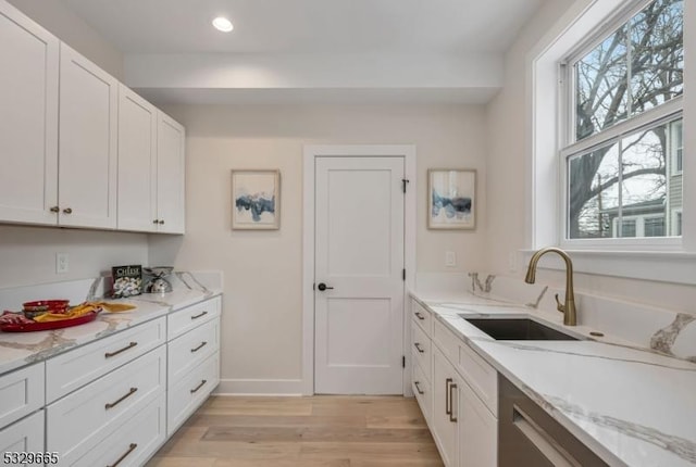 kitchen featuring a sink, light stone countertops, and white cabinets