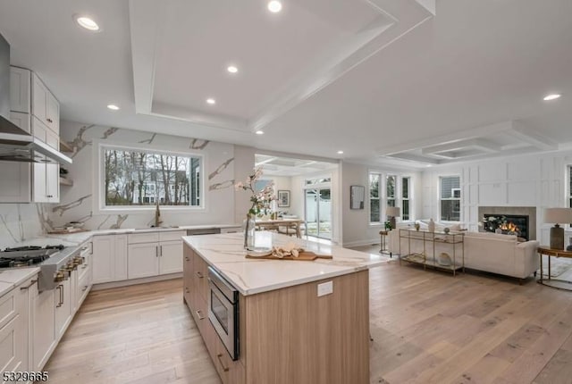 kitchen with a kitchen island, white cabinets, open floor plan, appliances with stainless steel finishes, and a raised ceiling