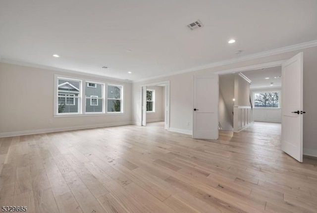 spare room featuring baseboards, light wood-style flooring, visible vents, and crown molding