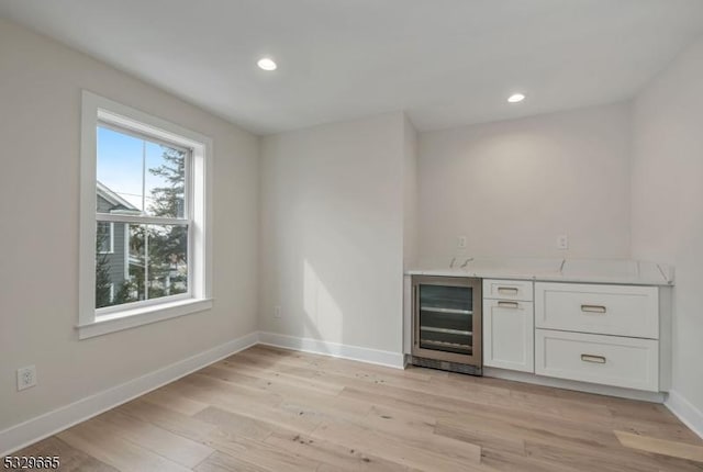 bar with wine cooler, recessed lighting, light wood-style floors, wet bar, and baseboards