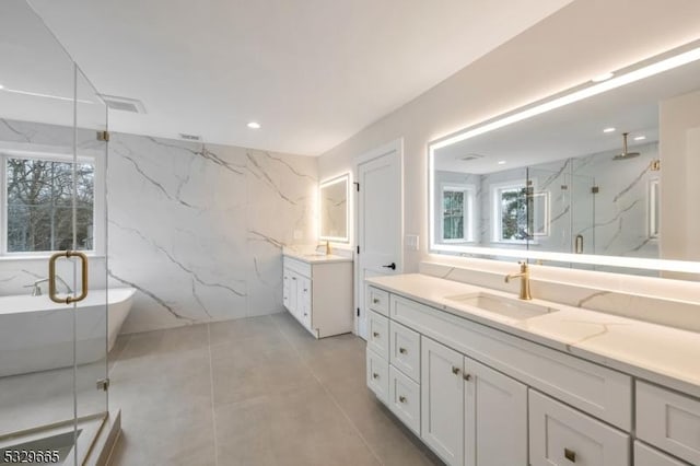 bathroom with plenty of natural light, two vanities, a sink, and a marble finish shower