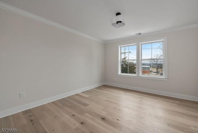 empty room featuring ornamental molding, baseboards, visible vents, and light wood finished floors