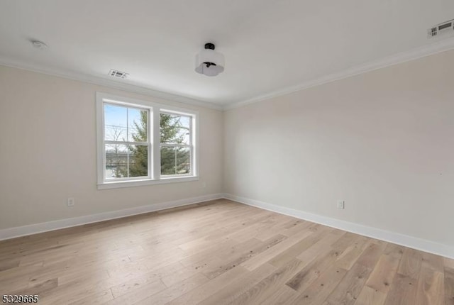 unfurnished room with baseboards, light wood-style flooring, visible vents, and crown molding