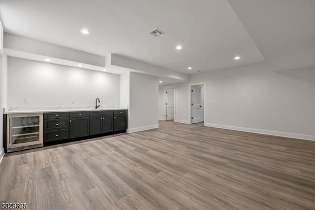 bar with baseboards, light wood-style flooring, indoor wet bar, a sink, and recessed lighting