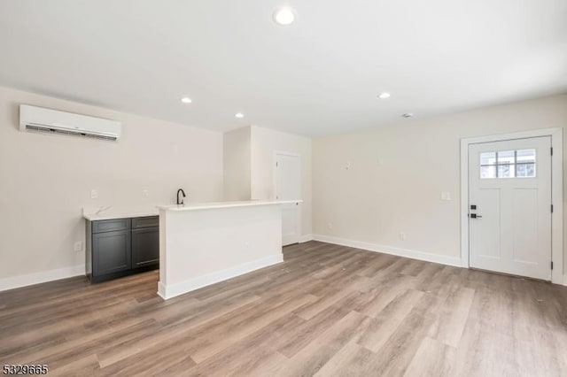 interior space featuring recessed lighting, an AC wall unit, light countertops, and light wood-style flooring