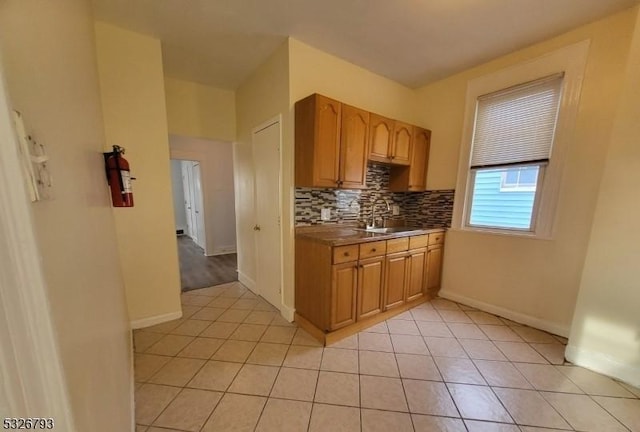 kitchen featuring tasteful backsplash, sink, and light tile patterned flooring