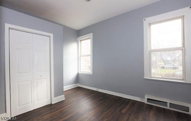 unfurnished bedroom featuring a closet, dark hardwood / wood-style flooring, and multiple windows