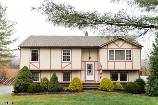 view of front of home with a shingled roof, a chimney, a front lawn, and stucco siding