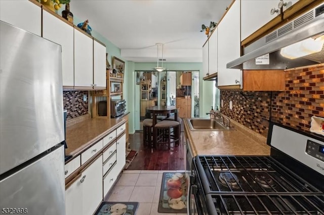 kitchen featuring decorative light fixtures, white cabinetry, sink, and appliances with stainless steel finishes