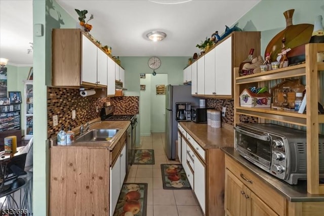 kitchen featuring decorative backsplash, appliances with stainless steel finishes, sink, white cabinetry, and light tile patterned flooring