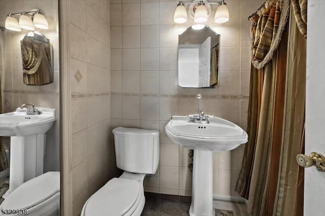 bathroom featuring toilet, sink, and tile walls