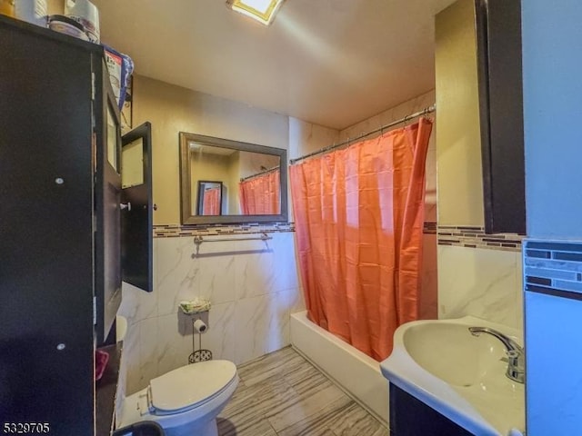 full bathroom featuring vanity, shower / bathtub combination with curtain, toilet, and tile walls