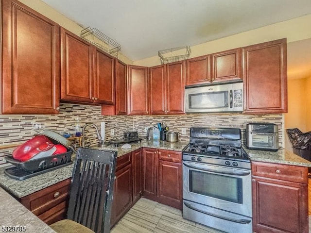 kitchen featuring decorative backsplash, stainless steel appliances, and light stone counters