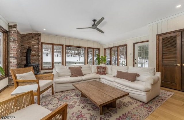 living room with lofted ceiling, light hardwood / wood-style flooring, a wood stove, and ceiling fan