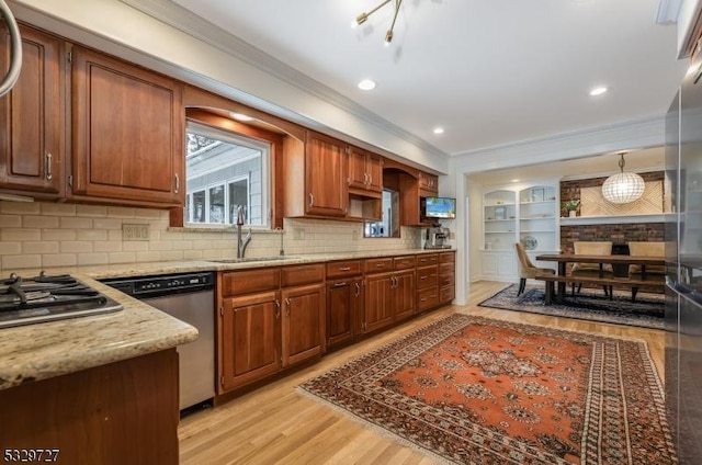 kitchen with pendant lighting, appliances with stainless steel finishes, tasteful backsplash, sink, and light wood-type flooring