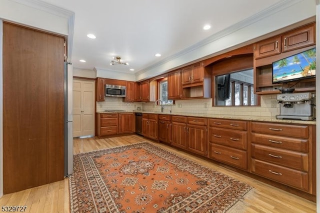 kitchen featuring stainless steel appliances, sink, backsplash, ornamental molding, and light wood-type flooring