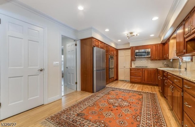 kitchen featuring sink, stainless steel appliances, light wood-type flooring, and decorative backsplash