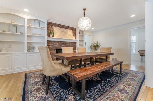 dining space with built in shelves, light hardwood / wood-style flooring, and ornamental molding