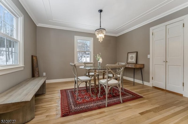 dining area featuring light hardwood / wood-style flooring, crown molding, and a chandelier