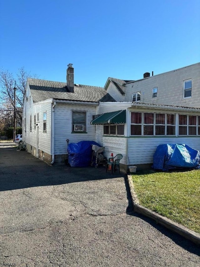 rear view of property featuring roof with shingles and a chimney