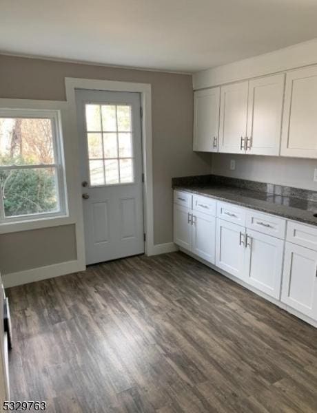 kitchen with a wealth of natural light, white cabinetry, dark stone countertops, and dark wood-type flooring