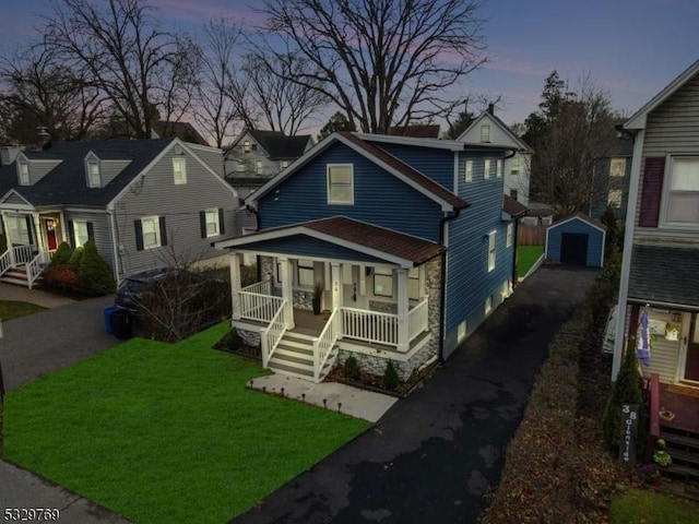 view of front of property with a yard, an outbuilding, covered porch, and a garage