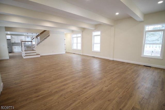 unfurnished living room featuring beamed ceiling and dark hardwood / wood-style floors