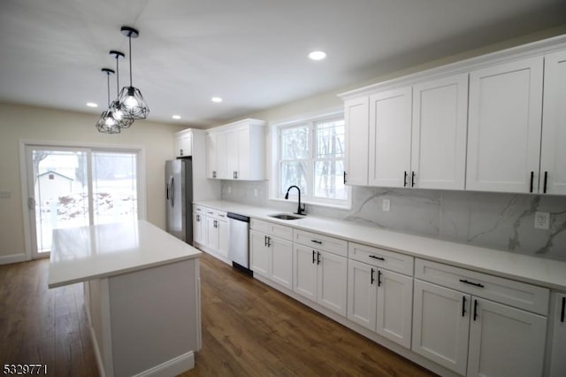 kitchen with appliances with stainless steel finishes, backsplash, sink, a center island, and white cabinetry