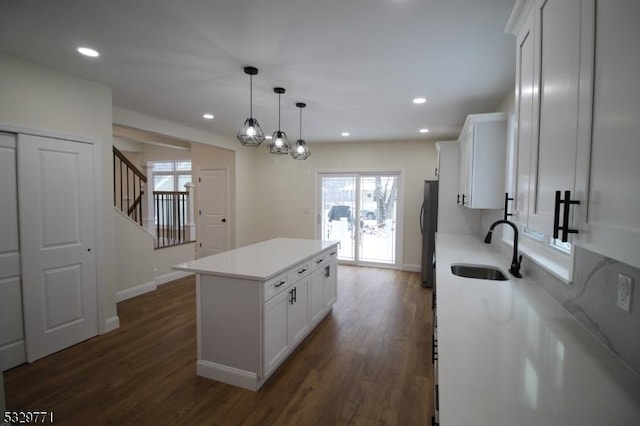 kitchen with white cabinets, a center island, hanging light fixtures, and sink