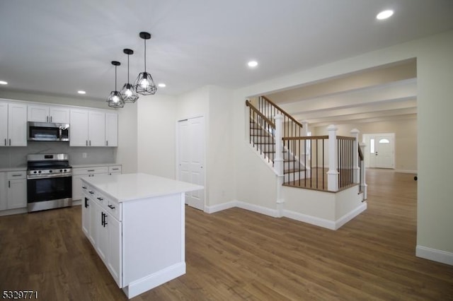 kitchen featuring hanging light fixtures, a kitchen island, dark hardwood / wood-style flooring, white cabinetry, and stainless steel appliances