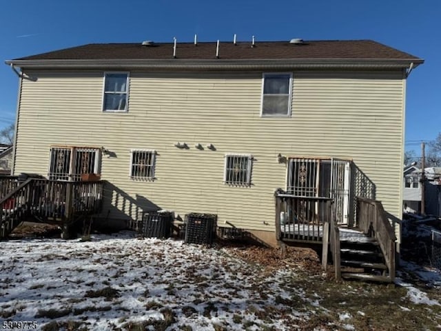 snow covered house featuring central AC and a deck