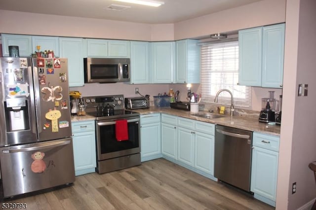 kitchen featuring light stone counters, light hardwood / wood-style floors, sink, and stainless steel appliances