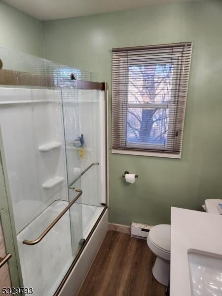 full bathroom with combined bath / shower with glass door, sink, hardwood / wood-style flooring, toilet, and baseboard heating