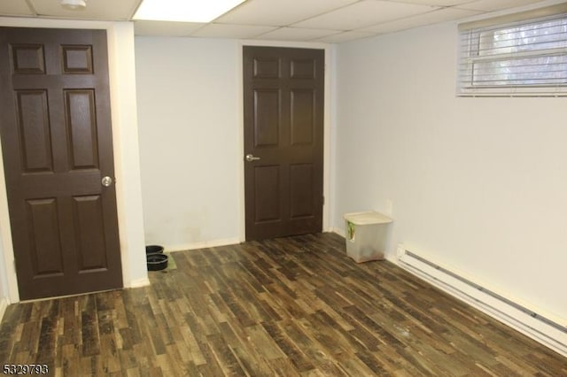 unfurnished room featuring dark hardwood / wood-style floors, a drop ceiling, and a baseboard heating unit