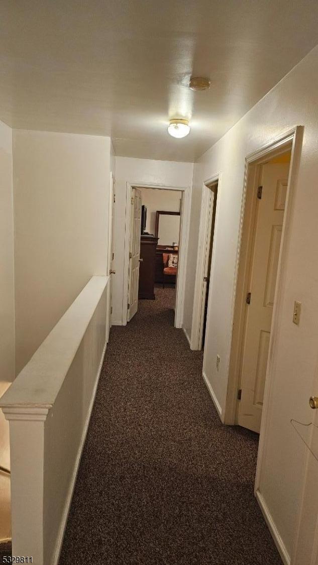 corridor featuring dark carpet