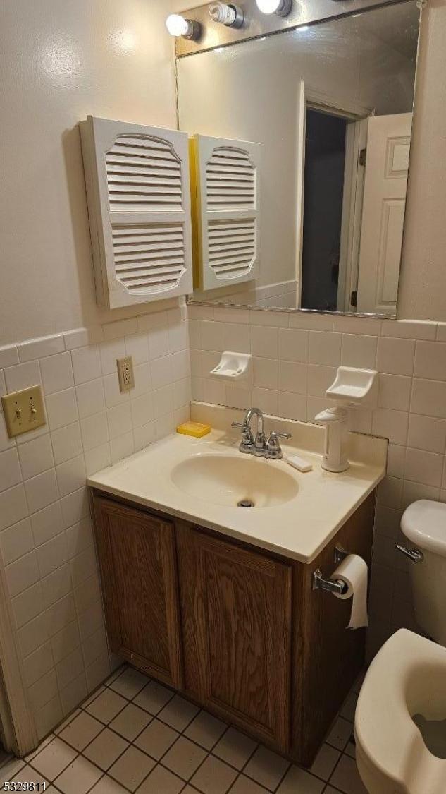 bathroom with vanity, toilet, tile patterned flooring, and tile walls