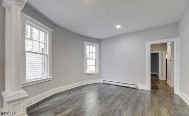 unfurnished room featuring dark hardwood / wood-style floors, ornate columns, and a baseboard heating unit