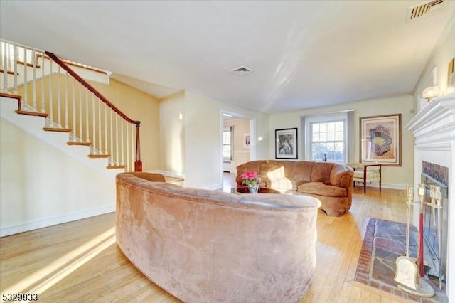 living room with light wood-type flooring and a brick fireplace