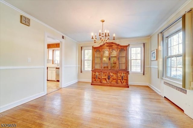 unfurnished dining area with radiator, a chandelier, light wood-type flooring, and ornamental molding