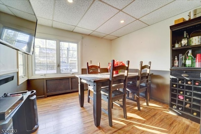 dining room with light hardwood / wood-style flooring and a drop ceiling