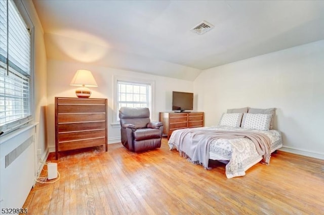 bedroom featuring hardwood / wood-style flooring, lofted ceiling, and radiator heating unit