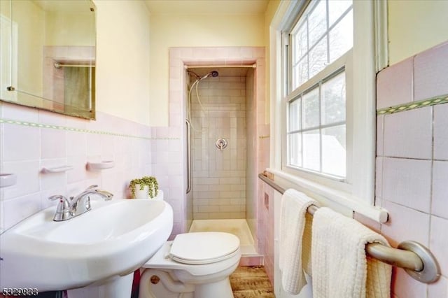 bathroom featuring a tile shower, sink, and toilet