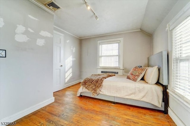 bedroom with light hardwood / wood-style floors, ornamental molding, and vaulted ceiling