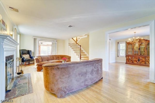 living room with a chandelier, light hardwood / wood-style floors, and ornamental molding