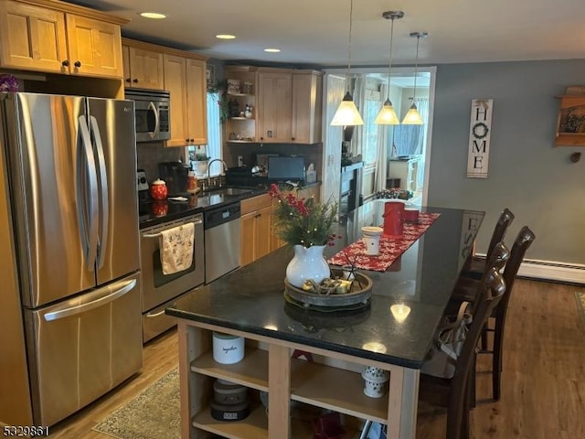 kitchen with sink, a center island, stainless steel appliances, a breakfast bar, and light wood-type flooring