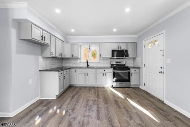 kitchen featuring appliances with stainless steel finishes, crown molding, dark wood-type flooring, sink, and gray cabinets