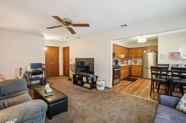 carpeted living room with ceiling fan