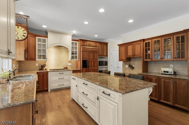 kitchen with double oven, sink, light hardwood / wood-style floors, and a center island